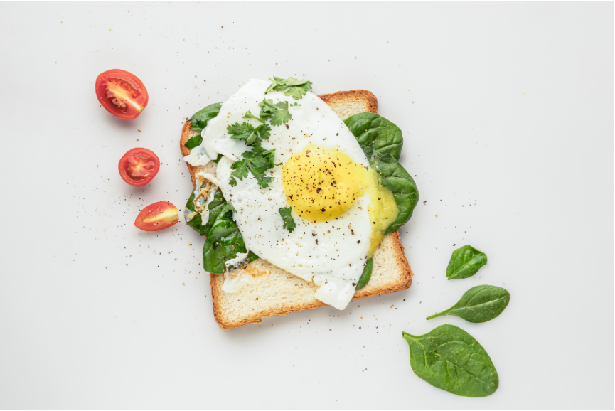 A poached egg on toast with spinach and tomatoes.