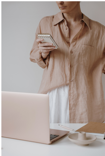 Career-driven woman standing by her desk looking at her phone.