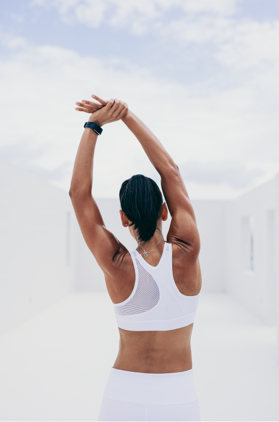 A woman in white gym attire is stretching.