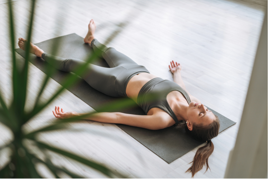 A woman on a fitness journey is lying on a yoga mat in savasana pose