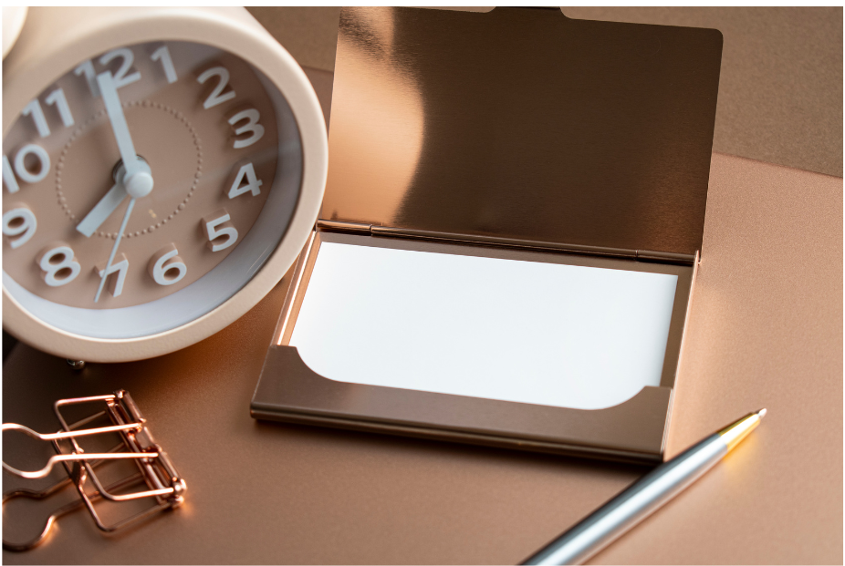 A clock, paperclip, pen, and notepaper on a side table.