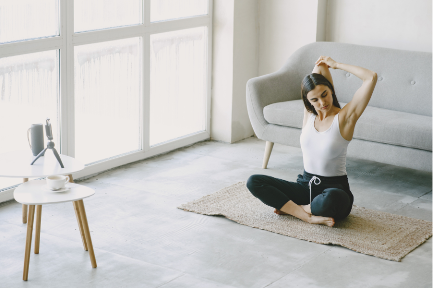 Women sitting on the floor and stretching her arms.