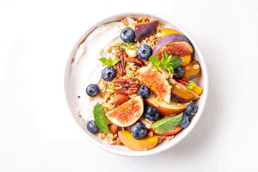 A yogurt smoothie bowl with oats, blueberries, pecans, figs, and mint leaves.