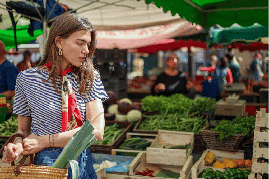 A woman shopping at a farmer's market as a conscious foodie.