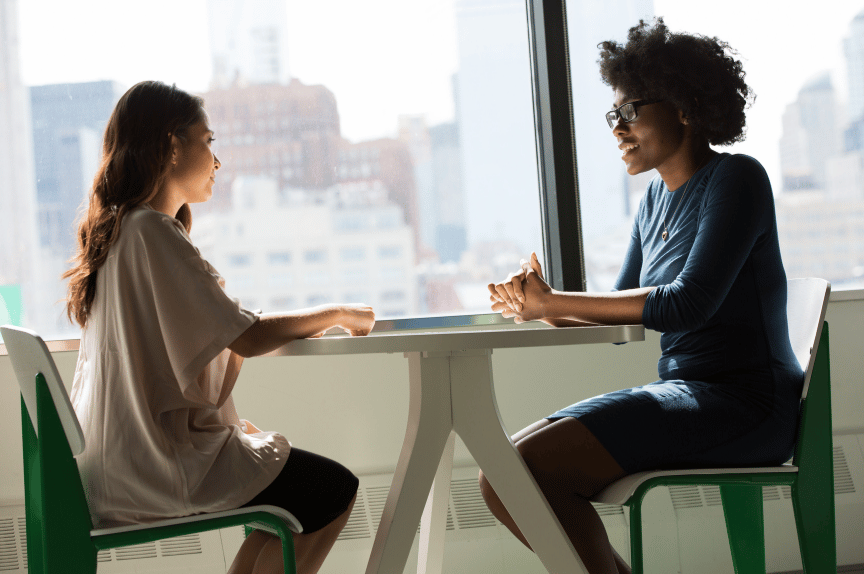 Two women having a conversation at work, showing how to help someone with burnout.