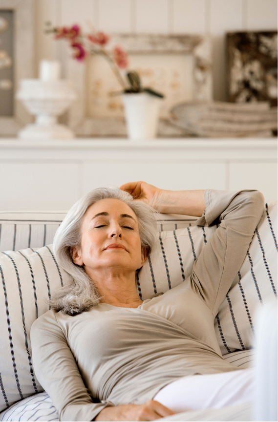 A woman is resting on a sofa.