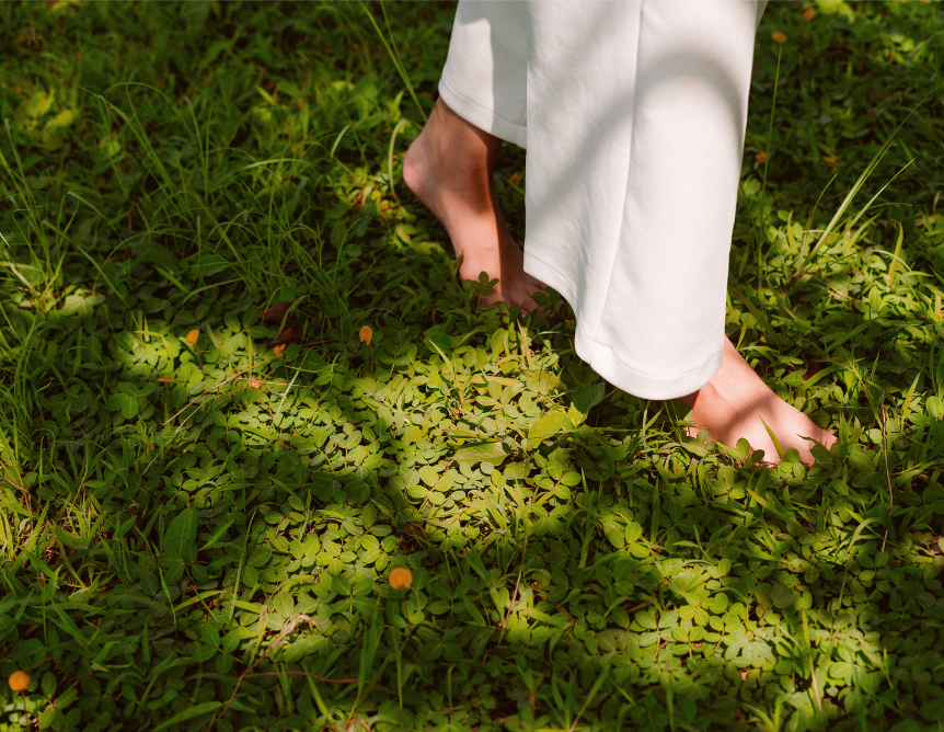 A woman walking barefoot on the grass.