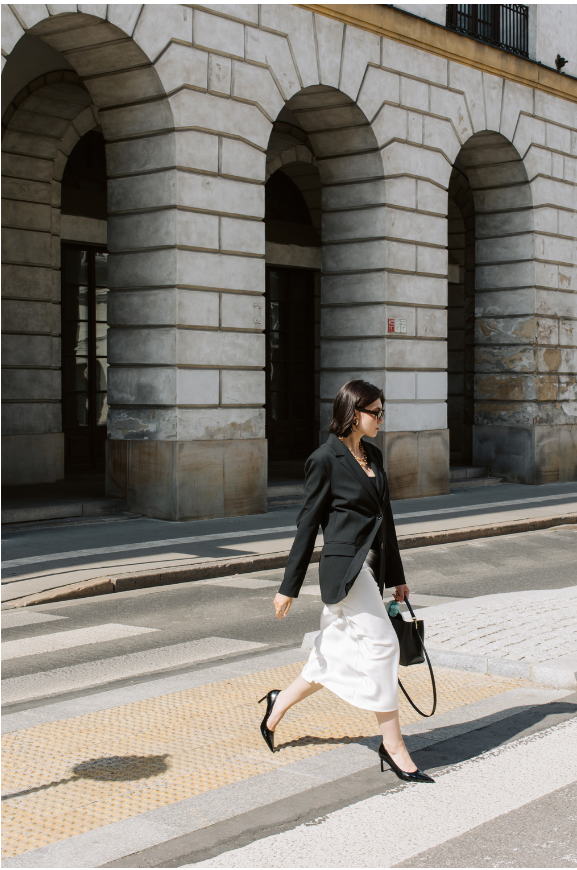 A confident successful business woman is crossing a street.