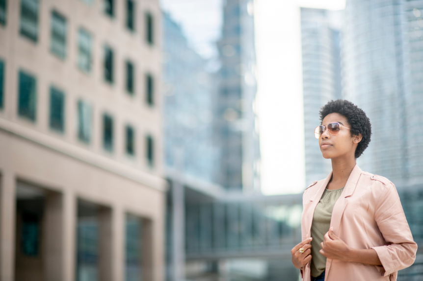 A business woman is standing on a street in a city.