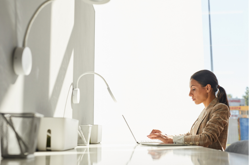 A business woman is in her office typing on a laptop computer.