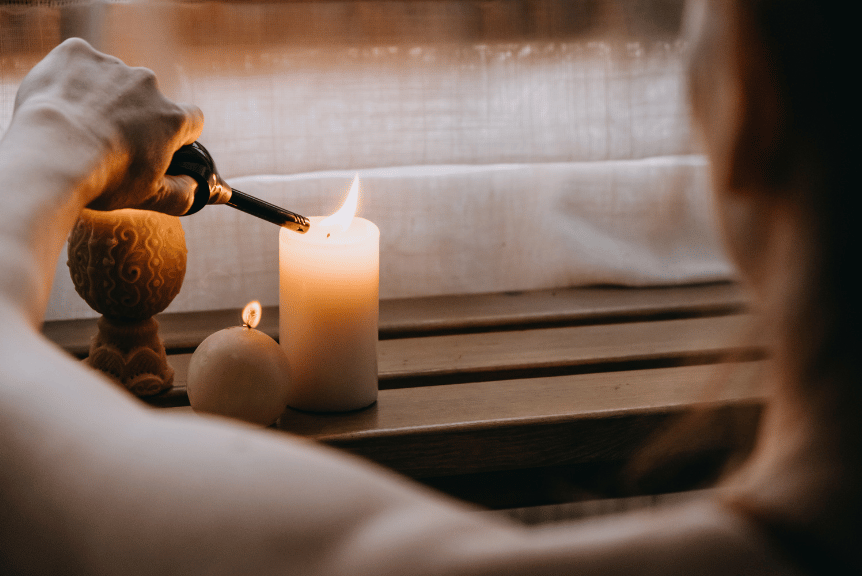 A picture of a woman lighting a candle as an example of a nourish and flourish ritual.