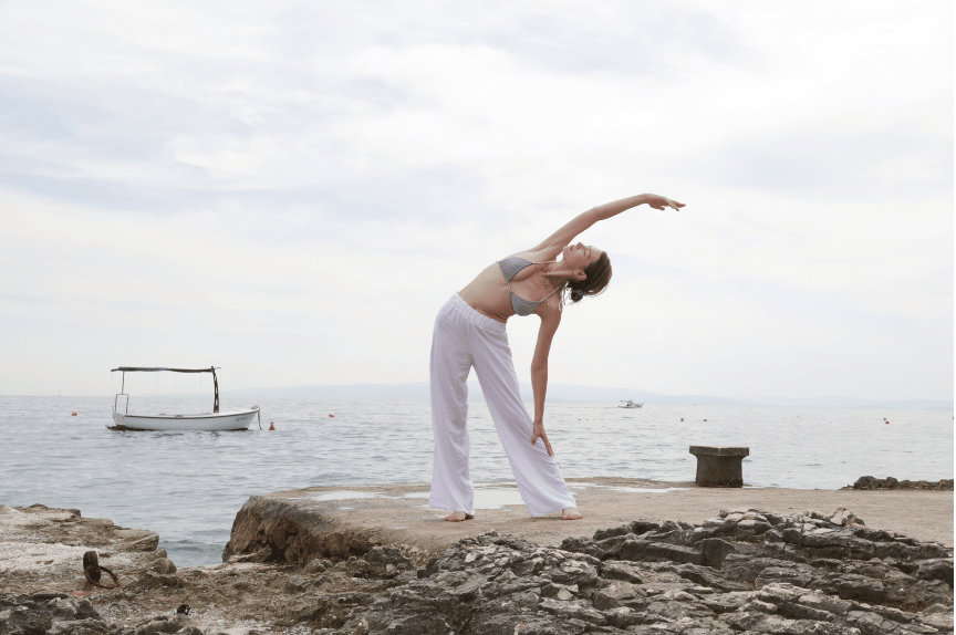 A picture of a woman doing yoga by the sea as a nourisher.