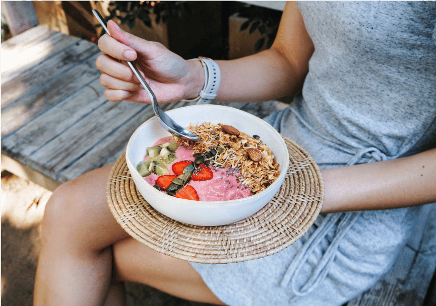 A picture of a woman eating a bowl of healthy food as a nourisher.