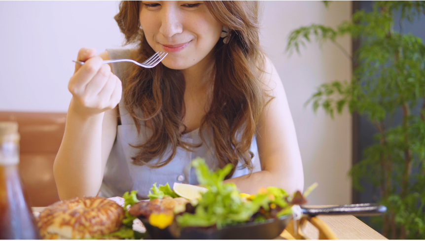 A woman smiling and enjoying food.