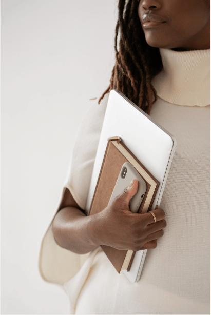 A career woman carrying a laptop, notebook, and phone.