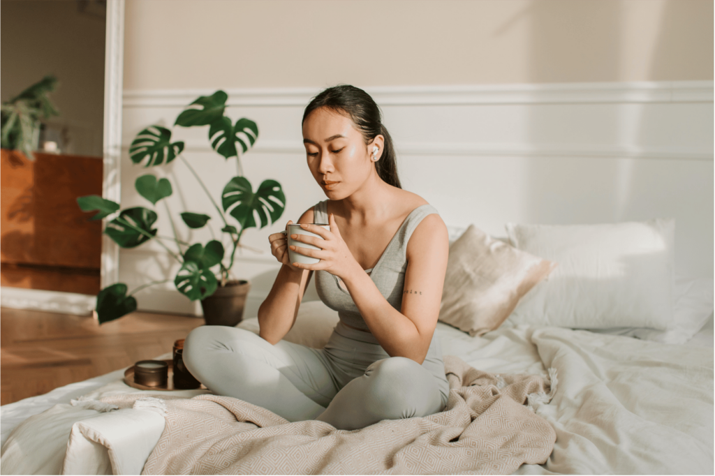 A woman slowly savoring tea while listening to music as an embodiment practice.